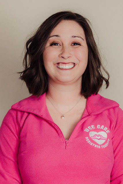White woman with brown hair parted down the side in pink polo smiles at the camera
